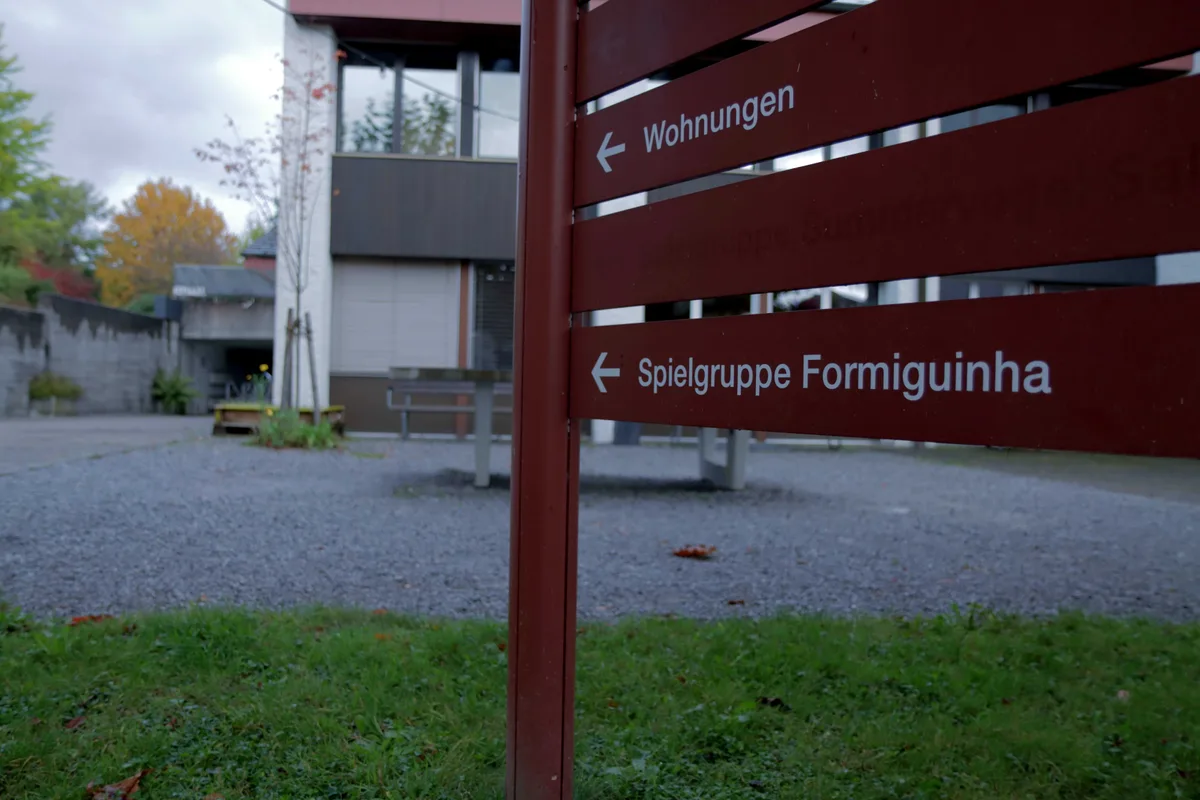 Ein rotes Wegweiserschild zeigt en Namen der Kita an.